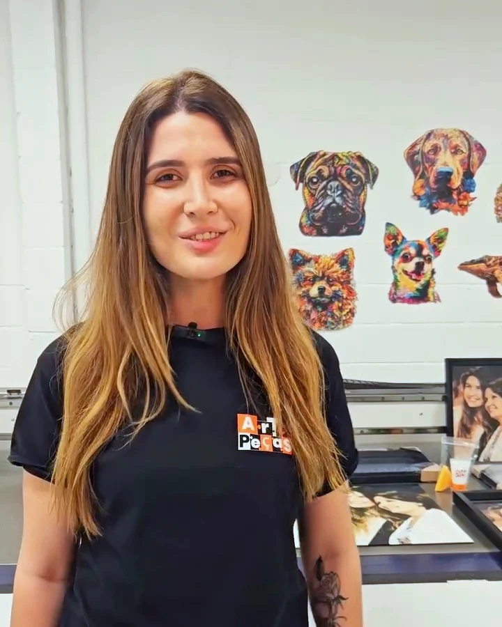 Juliana, da equipe da Mucci & Art, com a camiseta da Art em Peças na fábrica, com a impressora UV ao fundo